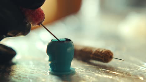 extreme close-up of tattoo artist dipping needle in inks