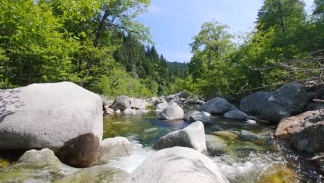 Emerald-pools-small-waterfall-through-rocks-into-clear-running-water-creating-ripples-below-blue-sky-surrounded-by-green-pine-trees-at-tahoe-national-forest