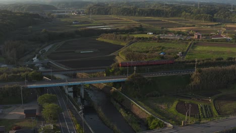 Rural-Train-in-Tottori-passing-Mikuriya,-Aerial-Tilt-Revealing-Mt-Daisen,-Japan