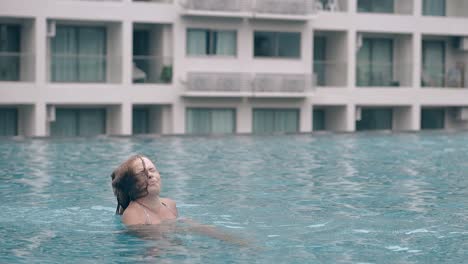 funny woman shakes hair in pool at exotic resort slow motion