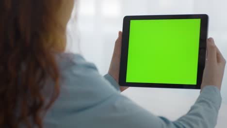 primer plano de una chica irreconocible viendo videos en línea en una tableta digital con pantalla clave de croma verde, espacio vacío