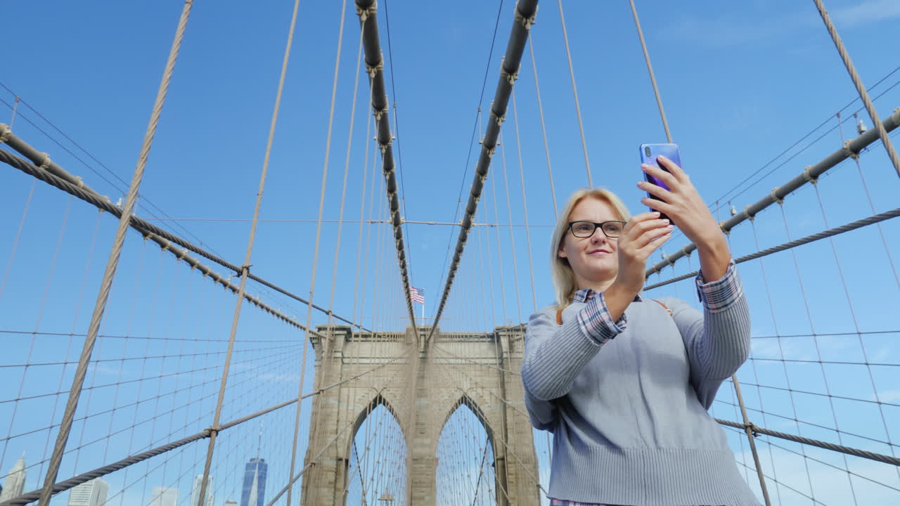 Una donna si scatta foto sul famoso Ponte di Brooklyn, una delle principali attrazioni di New York.