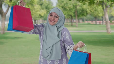 happy muslim woman doing shopping in park