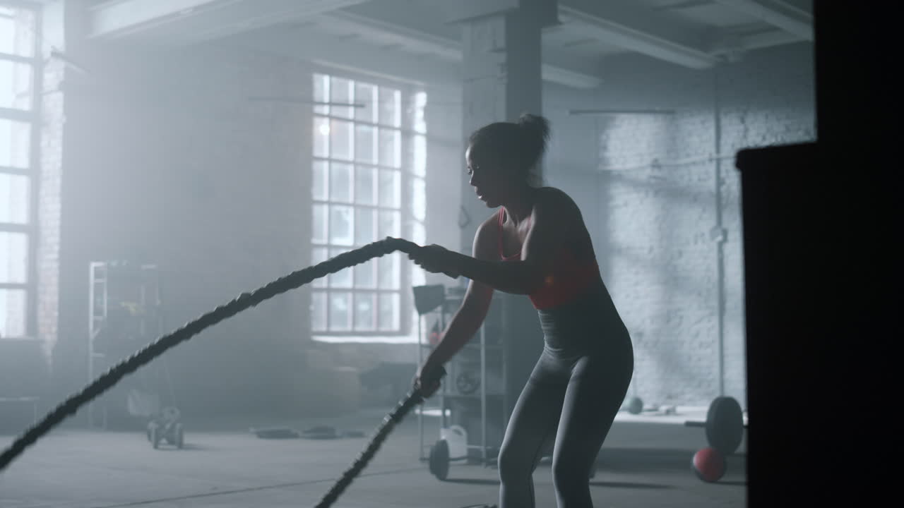 체조 선수 는 체육관 에서 전투 로프 운동 을 하고 있다. 여자 는 스포츠 클럽 에서 훈련 하고 있다