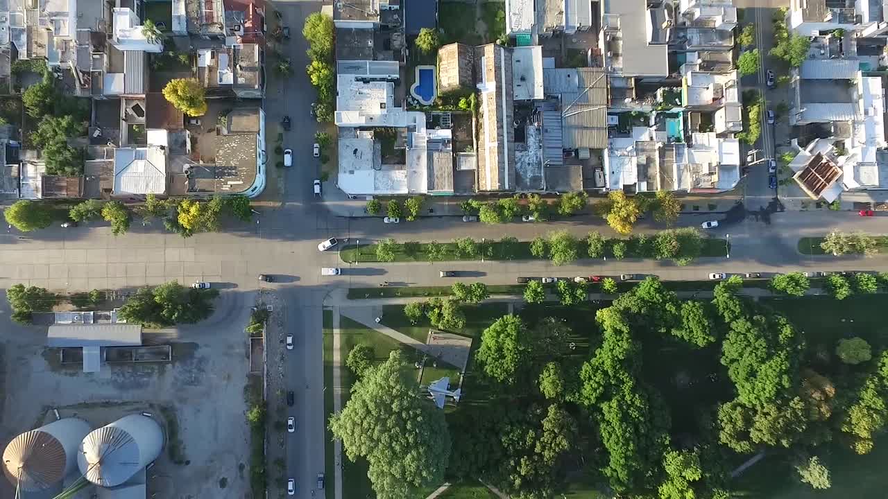 Drone Aerial top view of a city corner near a silo agriculture facility and a square with a war plane in it