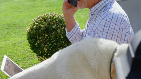 senior man talking on mobile phone while using laptop 4k