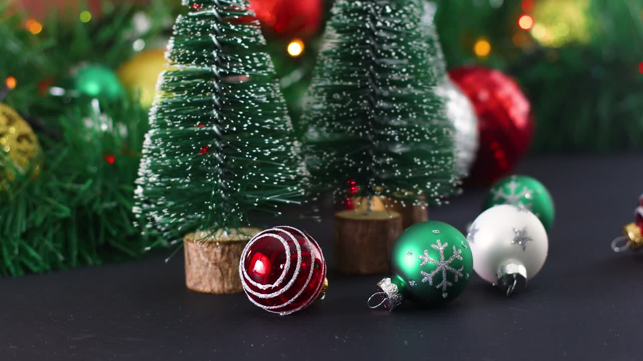 pequeños adornos de navidad y pinos de navidad con luces parpadeantes detrás