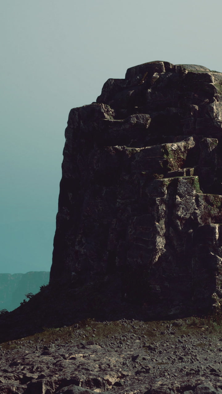 Tall rock outcrop near the water under a clear sky during daylight