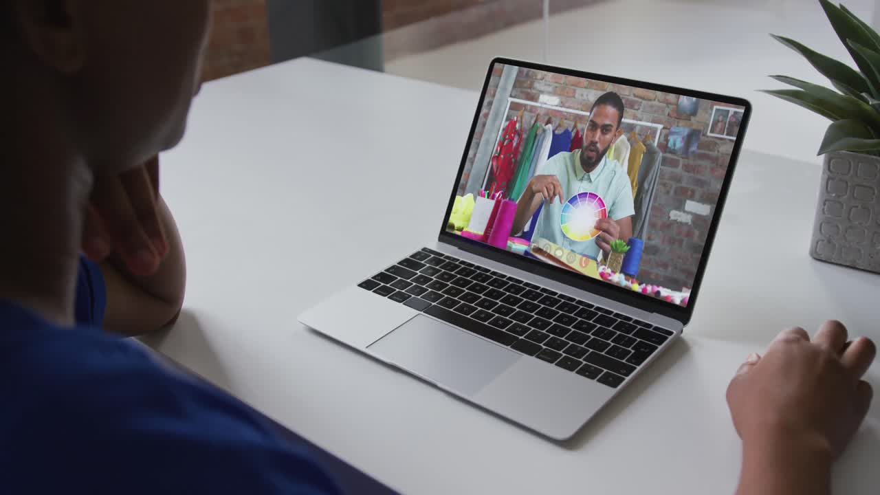 African american businesswoman sitting at desk using laptop having video call with male colleague