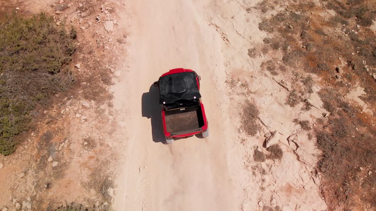 Carrellata ravvicinata che inquadra dall'alto un dune buggy a quattro ruote che sfreccia veloce su una strada sterrata.