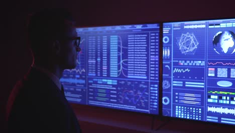 the man standing near the blue screen in a dark space