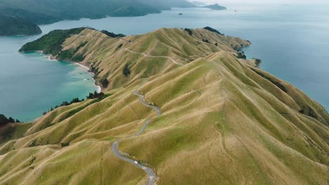 scenic aerial view of sloping peninsula landscape at te aumiti french pass with campervan traveling along winding road in marlborough sounds, south island of new zealand aotearoa