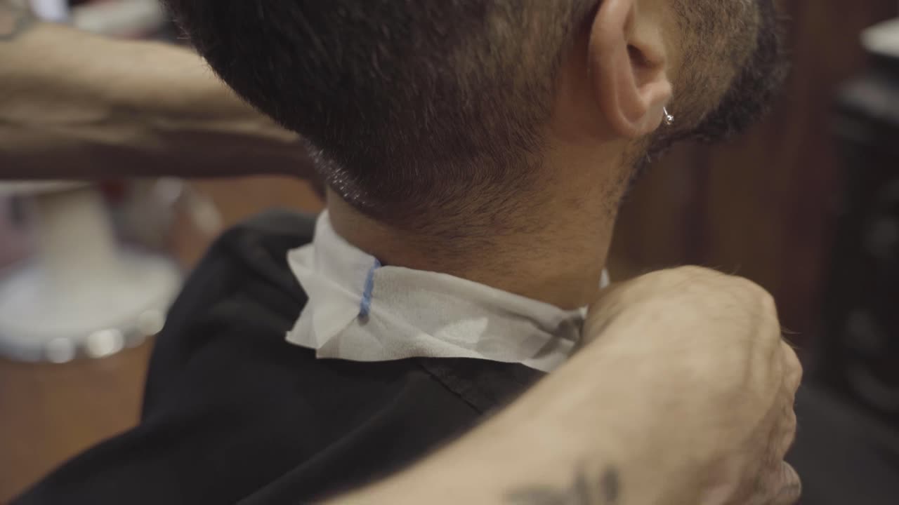 Barber Putting Neck Strip On Client's Neck In Barber Shop