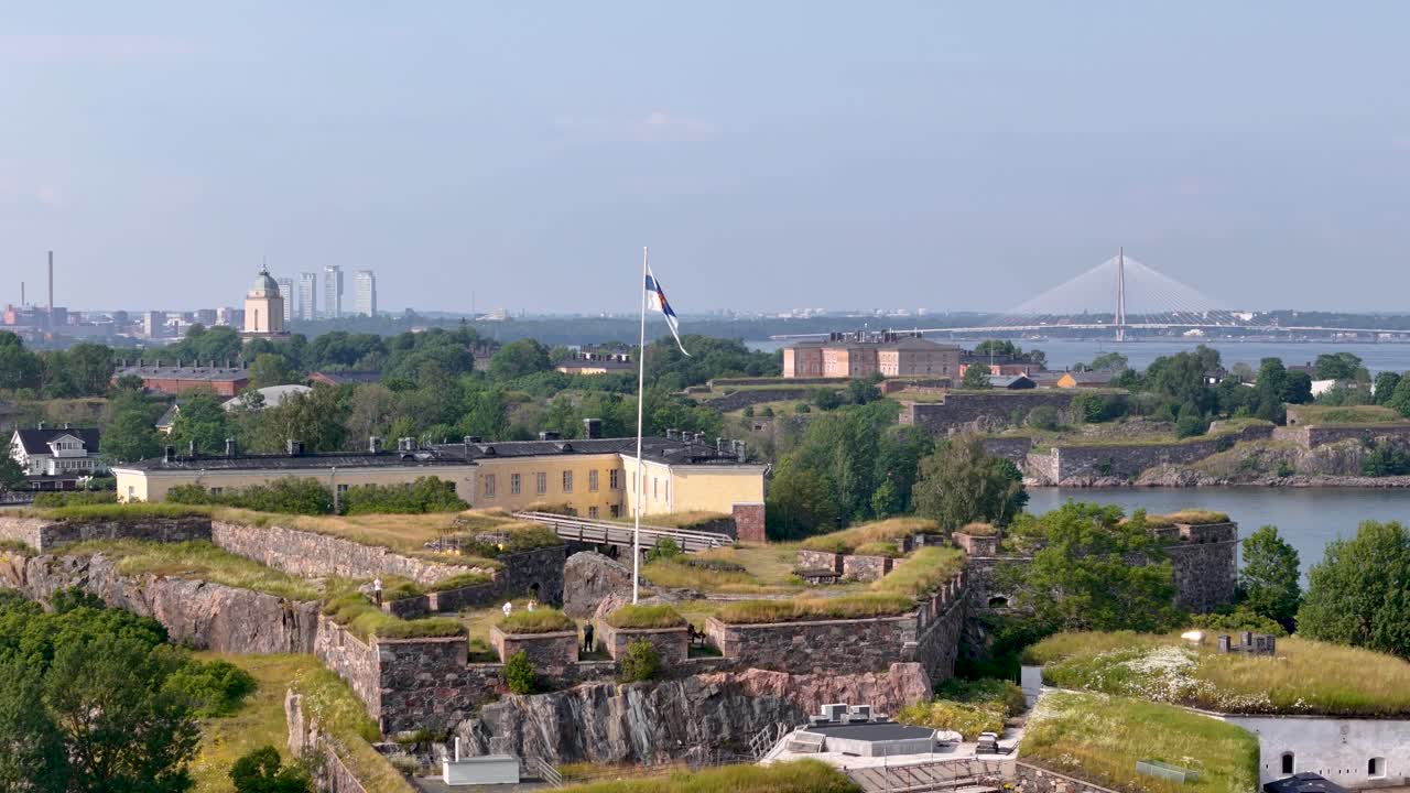 Slowly descending aerial view showing the historical Suomenlinna sea fortress and the city behind it in Helsinki, Finland