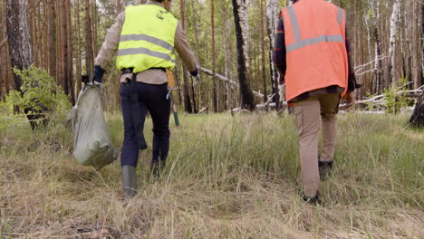 caucasian man activist carrying small trees in a sack and african american man holding a tablet