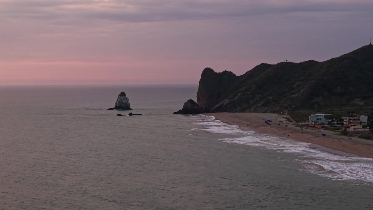 Splendida ripresa aerea della costa ecuadoriana con un faraglione e onde che si infrangono sulla riva al tramonto.