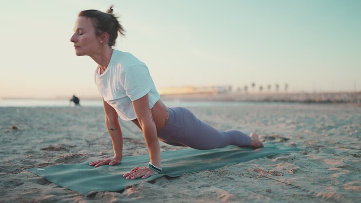 Caucasian woman exercising on yoga mat outdoors.