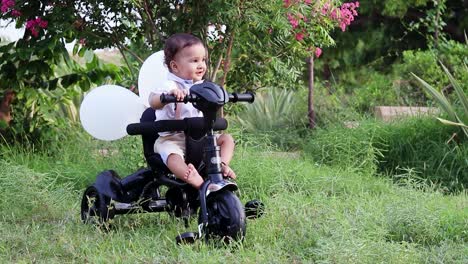 Un-Niño-Aislado-Sentado-En-Un-Triciclo-Con-Una-Sonrisa-Inocente-En-Un-Paño-Blanco-Jugando-Al-Aire-Libre