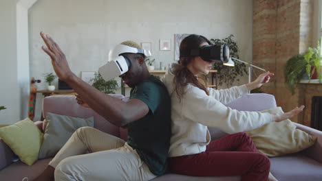 couple diversifié jouant à un jeu vidéo avec des casques vr à la maison