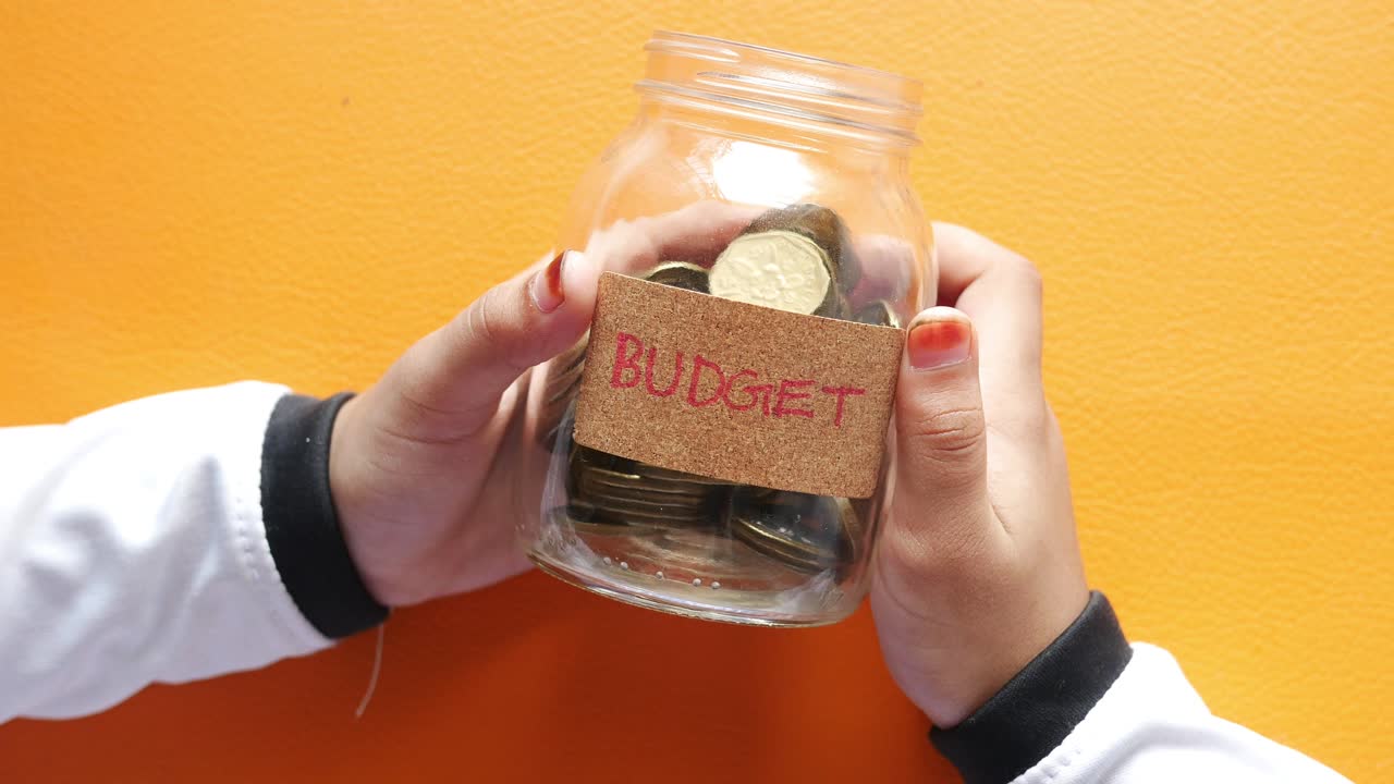Child girl holding jar of coins close up