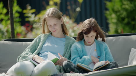 two girls read books, sit on a garden swing in the backyard of the house