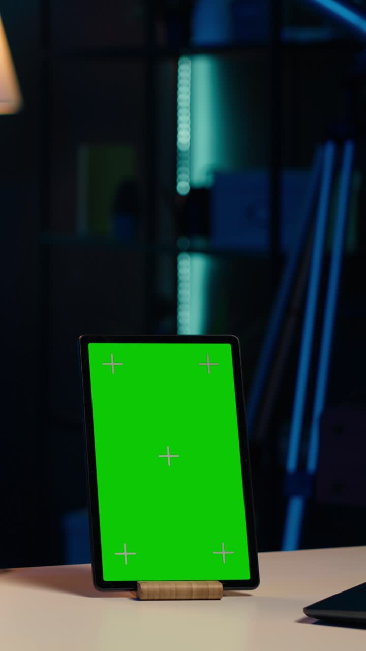 Vertical Tablet with Green Screen on Desk in Dark Room
