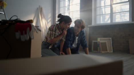 Young-couple-sitting-on-construction-background.-Family-discussing-blueprints.