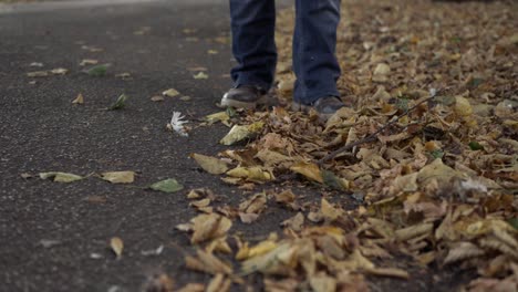 Legs-kicking-autumn-leaves-on-a-lane-wide-shot