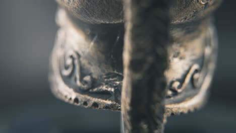 Un-Primer-Plano-Macro-Detallado-Desde-Detrás-De-Un-Diseño-De-Cara-Espartana,-Casco-Guerrero-De-Bronce-Griego-Antiguo,-En-Un-Soporte-Giratorio-De-360,-Iluminación-De-Estudio,-Movimiento-Suave-De-4k