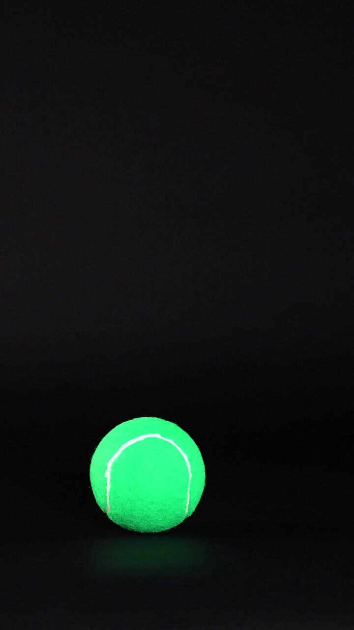 Tennis balls moving across a dark background