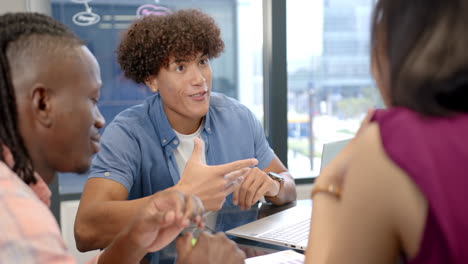 discussing project, diverse team collaborating using laptop in modern office setting
