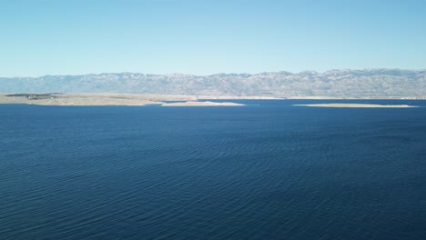 An-aerial-calm-view-over-deep-blue-Adriatic-Sea,-island-Pag-and-Velebit-mountain-in-Vrsi,-Zadar-region-Croatia