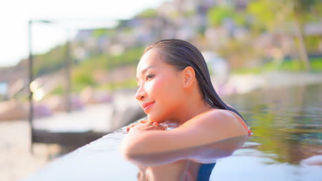 Profile-of-Beautiful-Exotic-Woman-on-Swimming-Pool-Border-looking-at-Sea-on-Hot-Summer-Day,-Slow-Motion