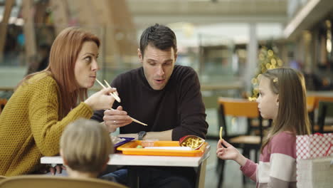 family eating a casual meal in a mall food court during the holiday season