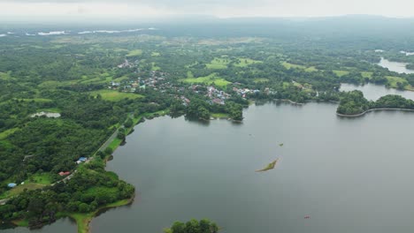 a slow, steady drone hovers over a calm lake surrounded by lush greenery, with light fog adding a soft, dreamy atmosphere to this peaceful laguna landscape