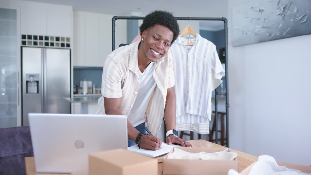 Uomo che legge un ordine dal laptop, scrive etichette e impacchetta una maglietta in studio, guidato da icone animate di e-commerce.