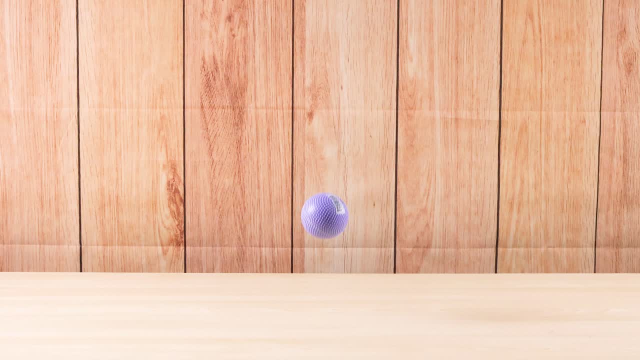 A purple ball bounces on wooden floor