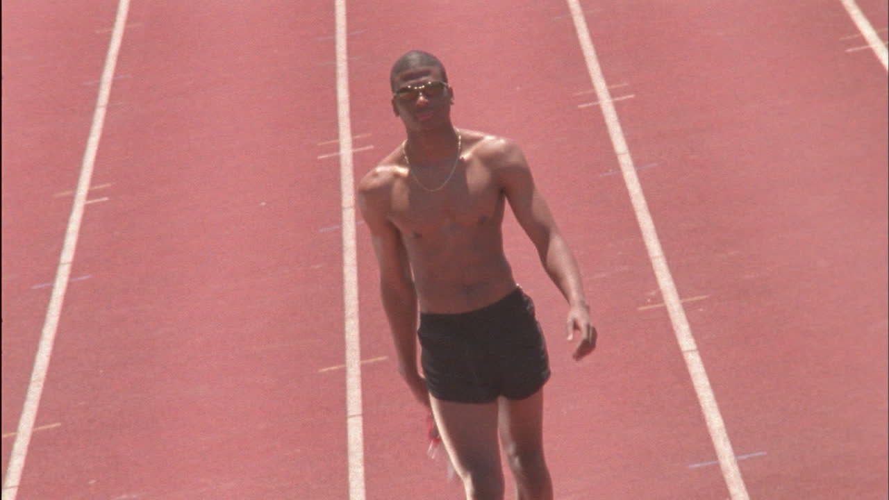 un hombre sale de un campo de carreras con zapatos en la mano