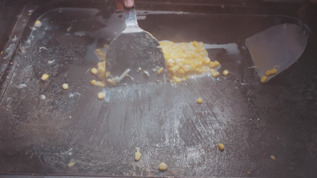 Vendor grills Taiwanese street food corn topped with melting cheese, creating a deliciously smoky and creamy treat at a bustling night market