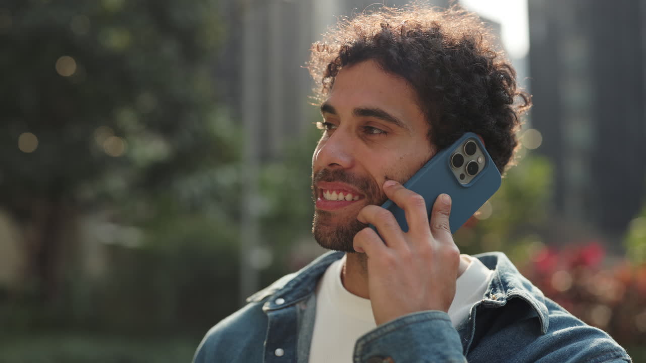 Young Man Talking on Mobile Phone and Smiling Outdoors