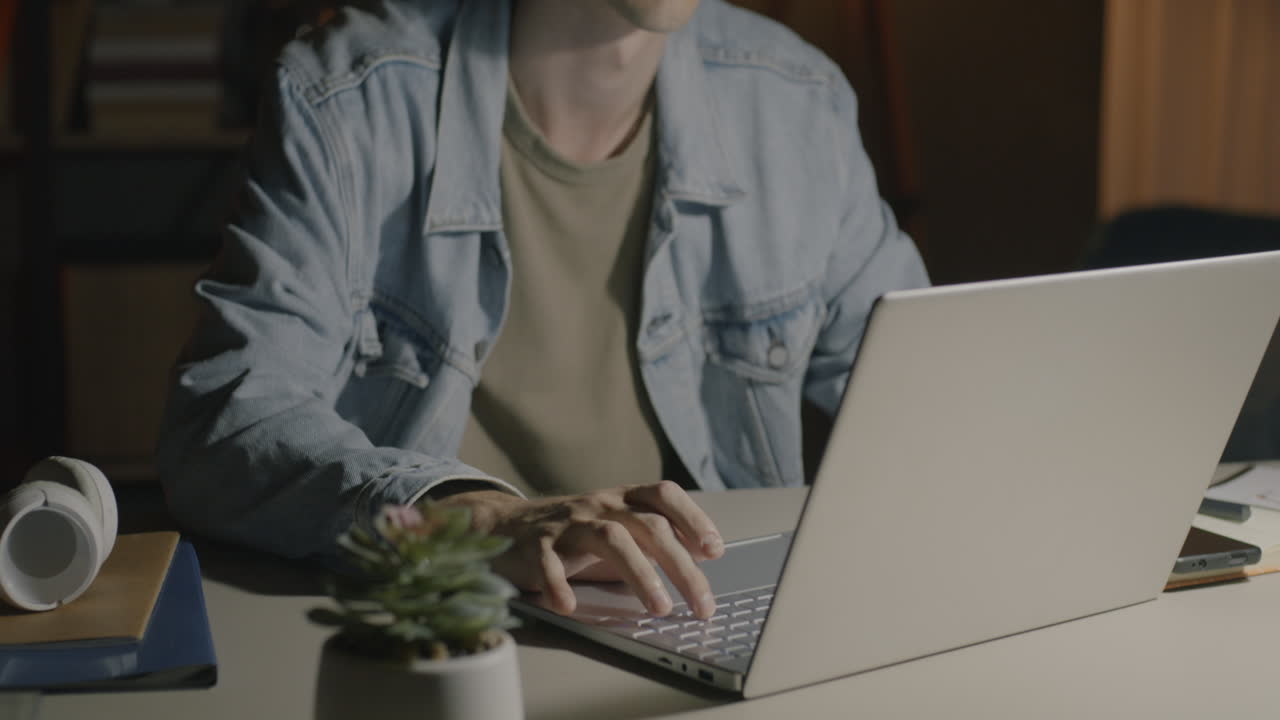 Молодой человек работает допоздна за ноутбуком