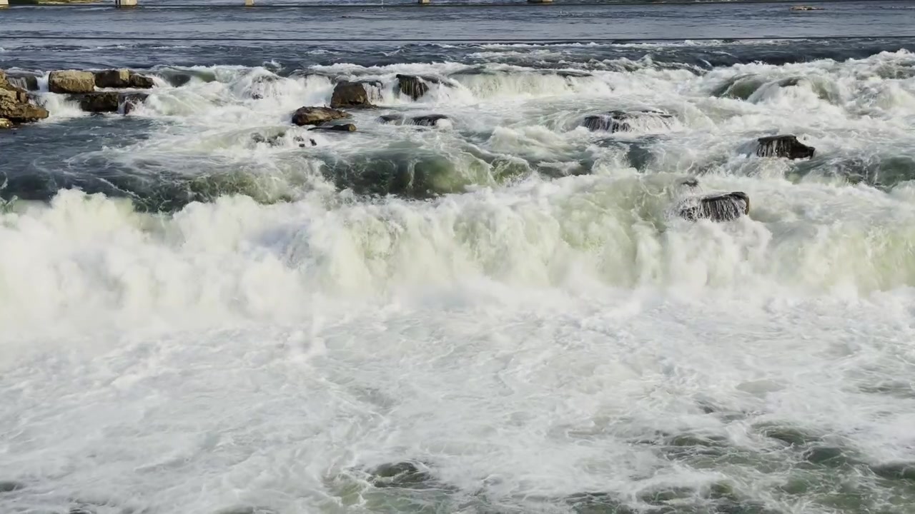 Rapide di fiume impetuose che si infrangono su rocce scure con acqua bianca spumeggiante, forte movimento della corrente naturale e un drammatico paesaggio esterno!