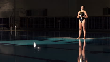 female swimmer with trophy at night pool