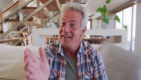 Portrait-of-senior-caucasian-man-talking-looking-at-camera-while-sitting-on-couch-at-home