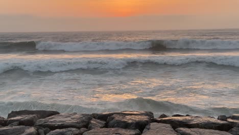 Der-Ruhige-Blick-Auf-Den-Sonnenuntergang-Und-Das-Meer-Verwandeln-Den-Horizont-In-Eine-Atemberaubende-Leinwand-Aus-Farben-Und-Licht-Mit-Wellen,-Die-An-Den-Wellenbrechern-Brechen