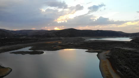 Aerial-drone-wide-fly-by-of-dried-up-Irvine-Lake-in-Southern-California-at-beautiful-sunset--lake-is-almost-empty-due-to-drought