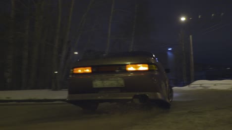 modified car drifting on snowy street at night