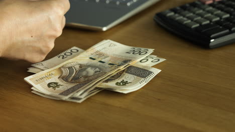 Female-hands-counting-200-Polish-zloty-bills-at-the-table---small-business-or-house-budget-concept,-close-up-shot