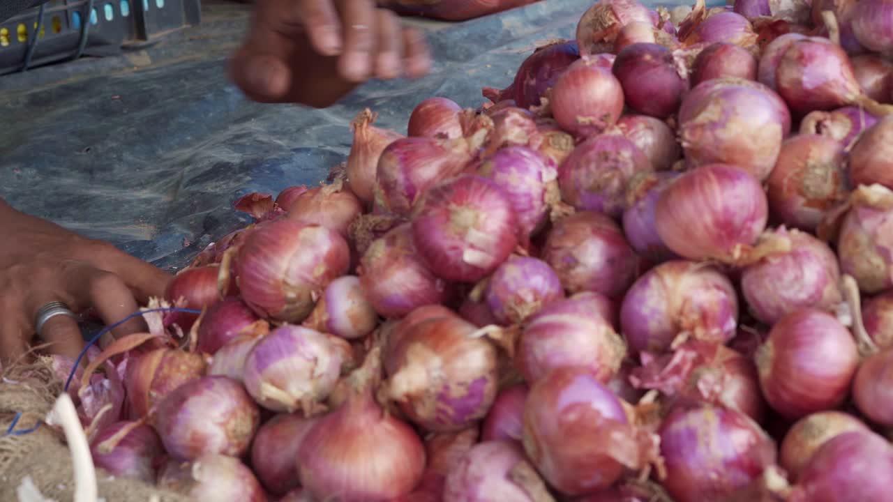 Indian female hands moving red onion on a market stand close up, Seggregating Onions
