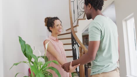 feliz pareja biracial abrazándose con alegría en la nueva casa
